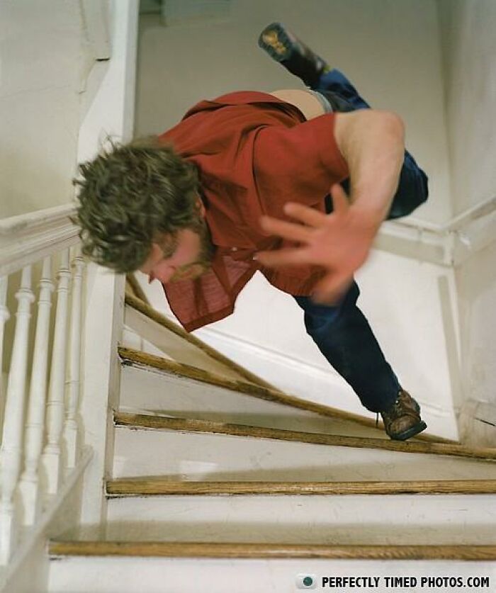 Man falling on stairs captured in a perfectly timed photo showing dynamic motion and balance loss indoors.