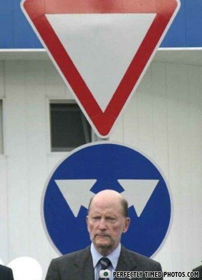 Man standing under road signs with arrows, creating a perfectly timed photo with an impressive visual effect.