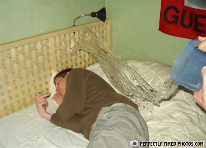 Man sleeping on bed as water is perfectly timed mid-air, captured in a truly impressive photo.