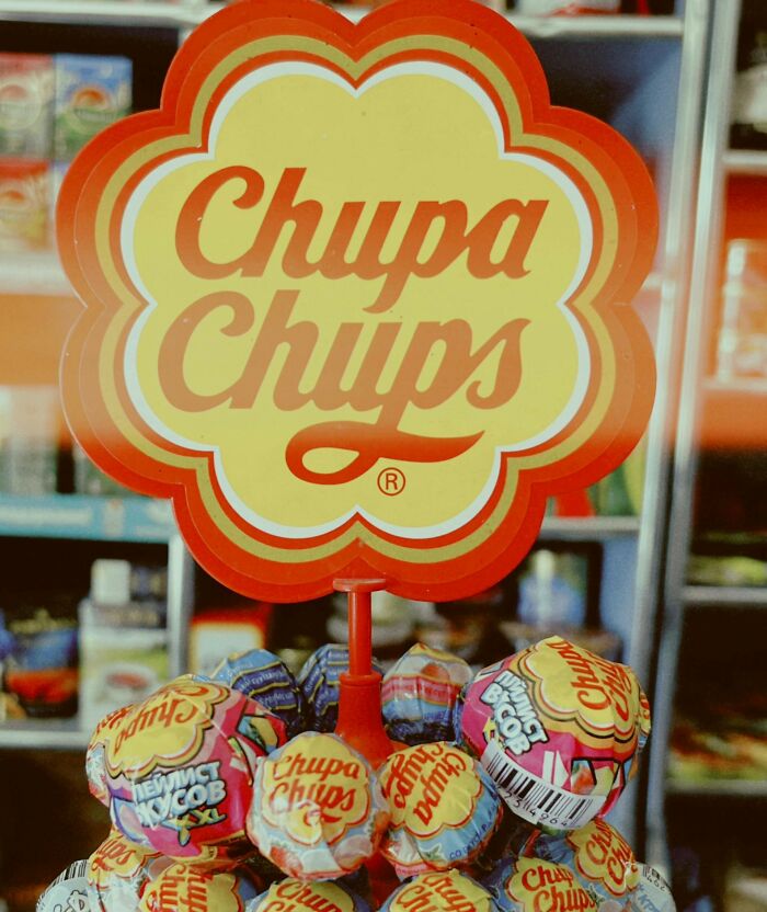 Chupa Chups lollipops displayed with people share historical facts unknown until recently in a colorful store setting.