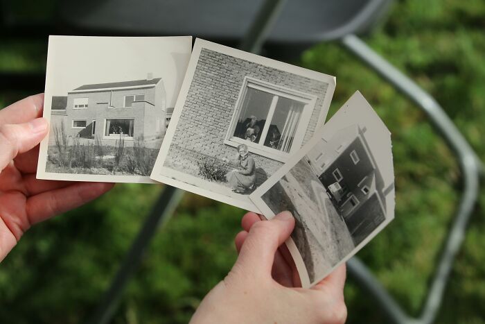 Hands holding old black and white photos of houses, evoking unresolved mysteries people carry with them emotions.
