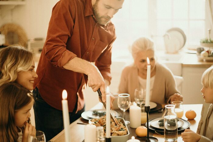 Family gathered around a candlelit table having dinner, illustrating reactions to horrible Christmas gifts.