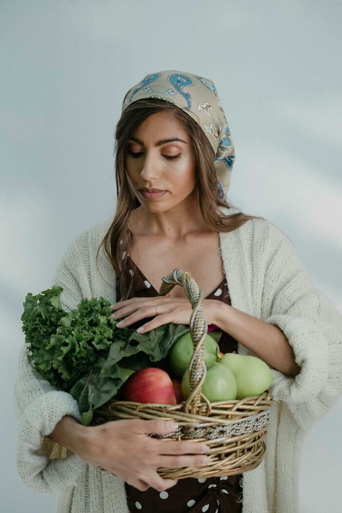 Woman in headscarf holding basket of fresh apples and greens, illustrating people displaying pure entitlement behavior.