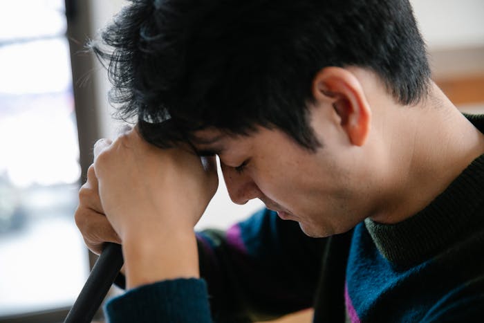 Young man upset and frustrated, resting his forehead on his hands after woman threw away cooked lunches.