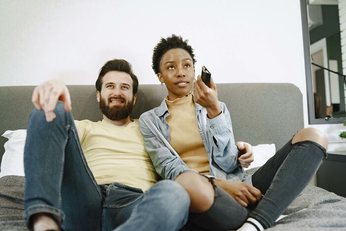 A couple sitting on a couch watching TV together, representing the smartest couch potato quiz concept.