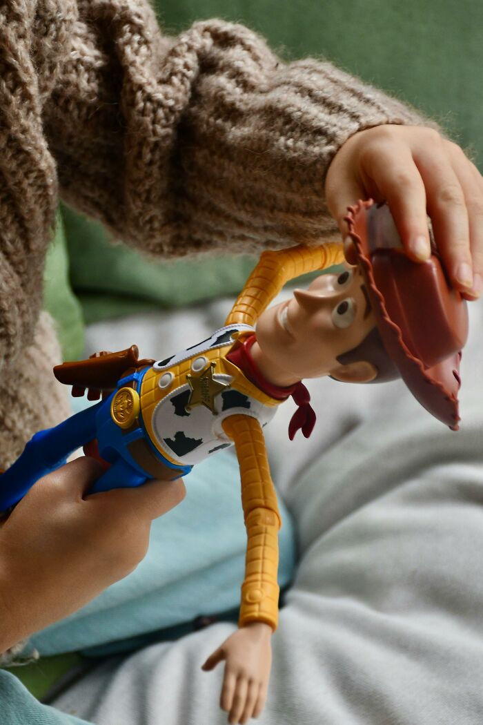 Child playing with a Woody toy figure, capturing innocent moments amid big family drama without any intention.