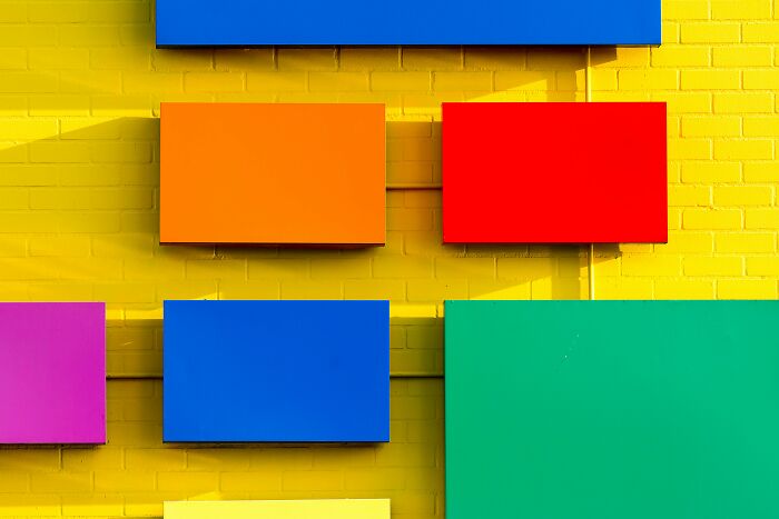 Colorful rectangular panels mounted on a bright yellow brick wall, highlighting creativity and sharp IQ test challenge.