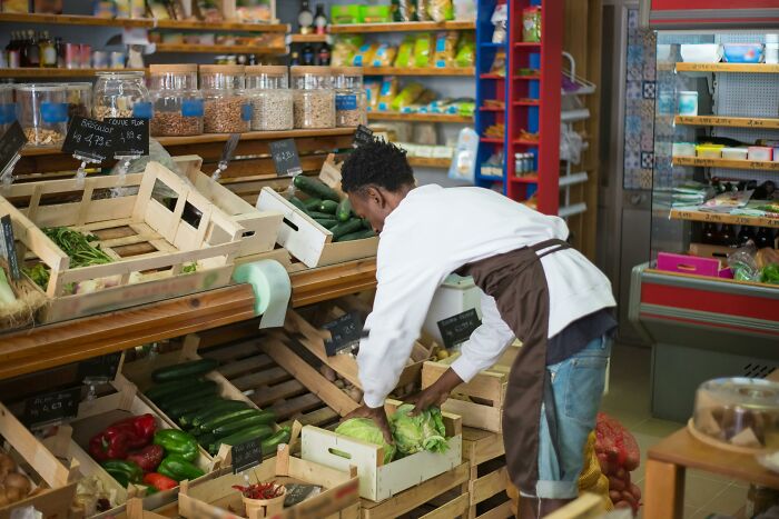 Employee arranging fresh produce in grocery store showcasing industry secrets shared by 33 employees about workplace realities.