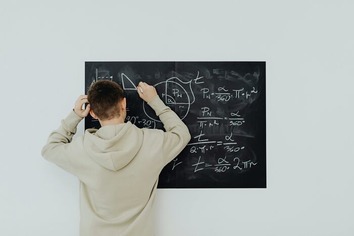 Student solving math problems on a blackboard, illustrating sharp math skills for an SAT quiz challenge.
