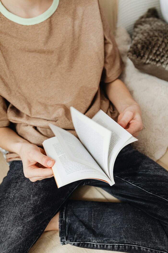 Person in casual clothes sitting and reading a book featuring funny clever and sassy sayings in the heat of the moment