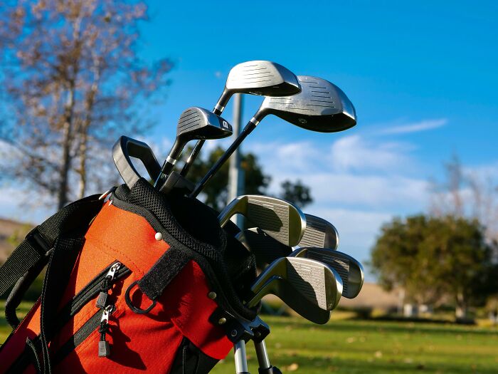 Golf clubs in an orange bag on a golf course under blue sky revealing dark dirty truths about industries hidden by employees