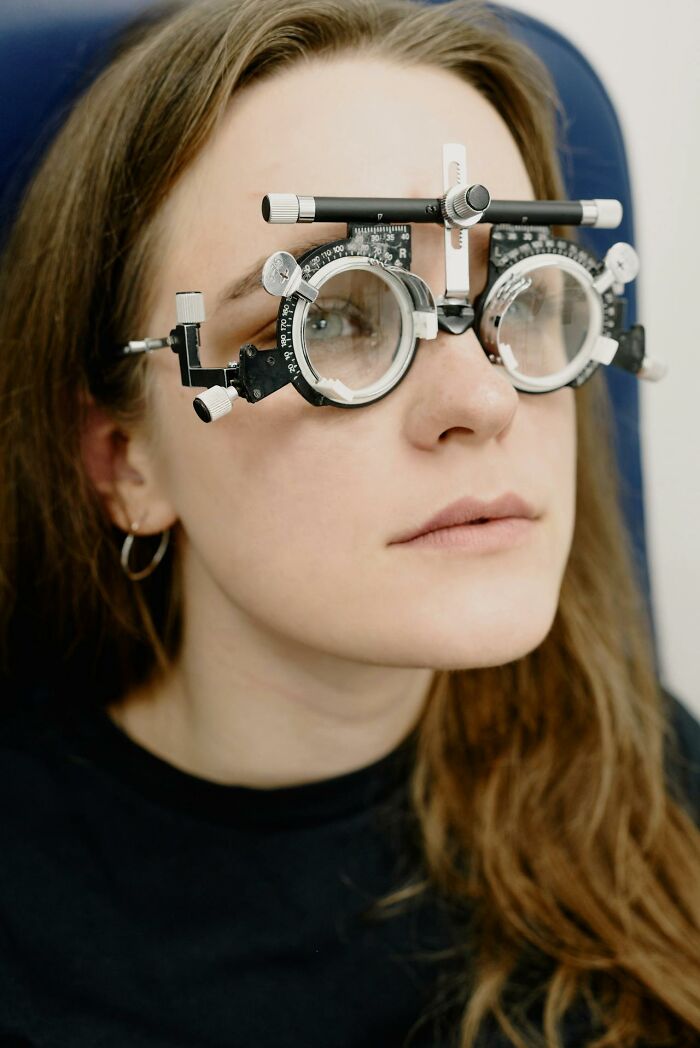 Woman wearing unusual optical testing glasses used for eye exams among unusual personal belongings at lost and found.