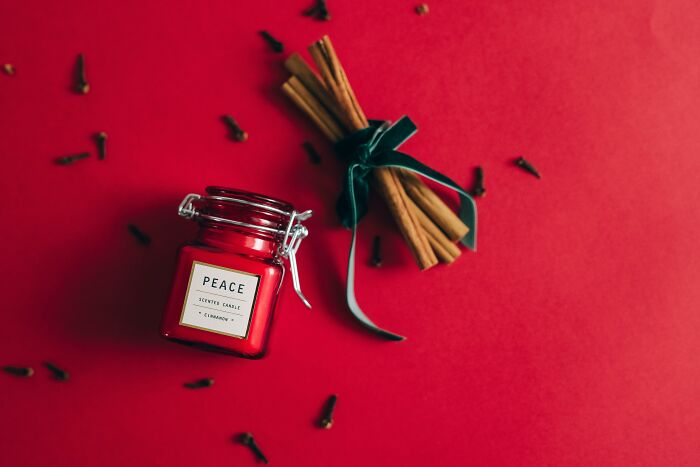 Red cinnamon scented candle and tied cinnamon sticks on red background representing horrible gifts for Christmas.