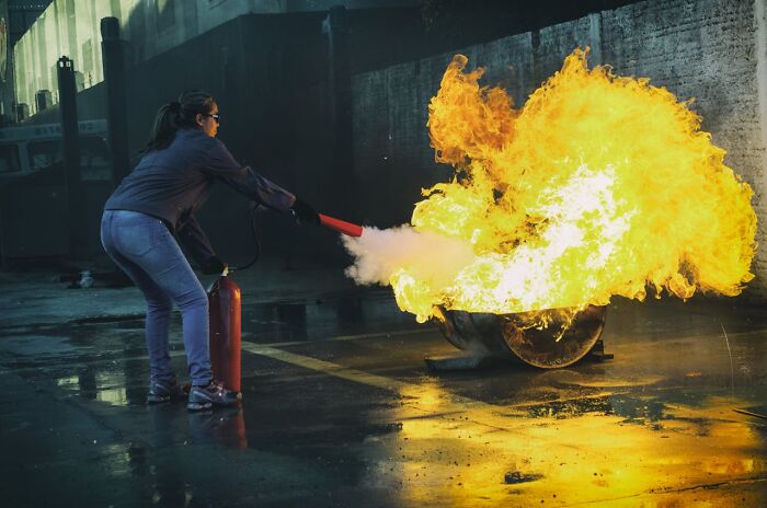 Person using fire extinguisher to put out large fire during an emergency, illustrating crazy airport stories and incidents.