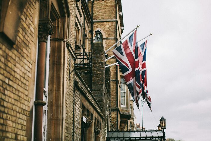 Union Jack flags flying outside a historic brick building in the UK, symbolizing the UK citizenship test challenge.