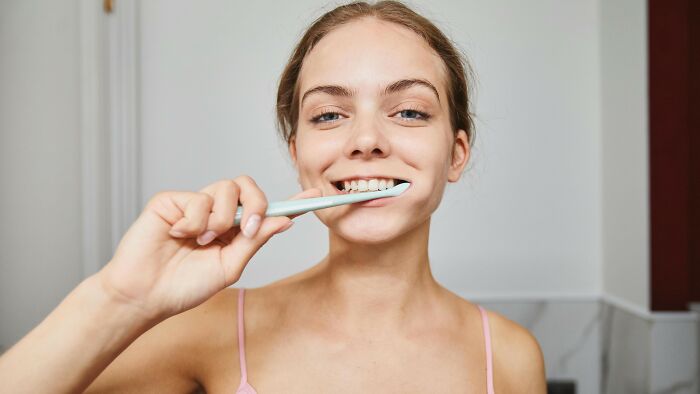 A women brushing her teeth in a casual wear.