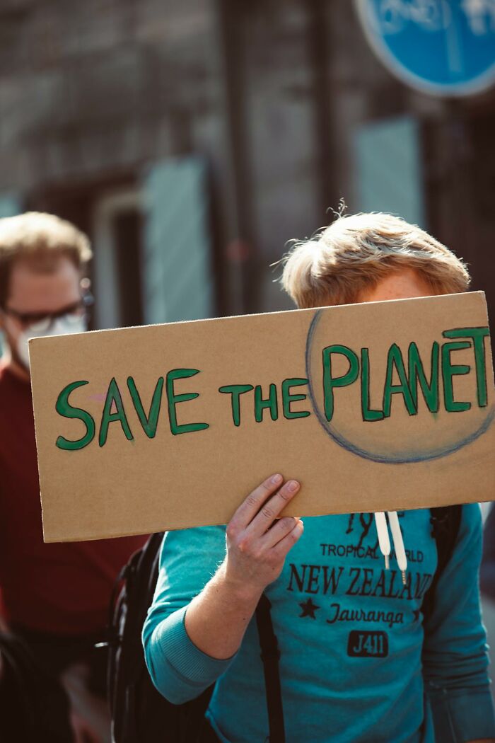 Person holding a cardboard sign with save the planet message during a protest about disturbing truths and environment.