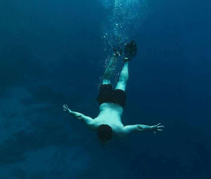 Man diving underwater in deep blue ocean, illustrating surprising life facts that might make you do a double take.