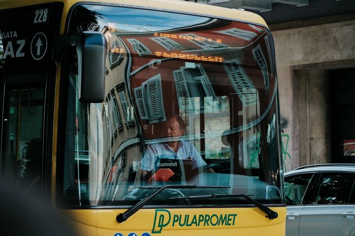 Bus driver inside a city bus with reflections, illustrating public frustration and displays of pure entitlement in daily life.