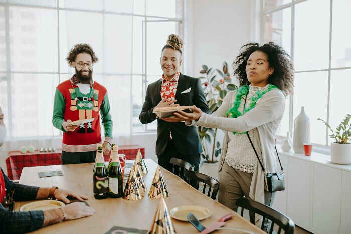 Group of people exchanging gifts at a holiday party, highlighting the theme of horrible gifts to avoid this Christmas.