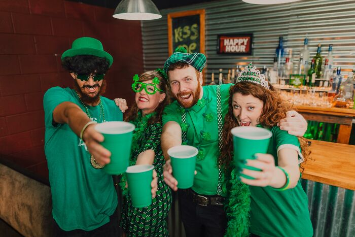 Group of friends dressed in green celebrating with drinks, showcasing Irish slang culture and festive party spirit.
