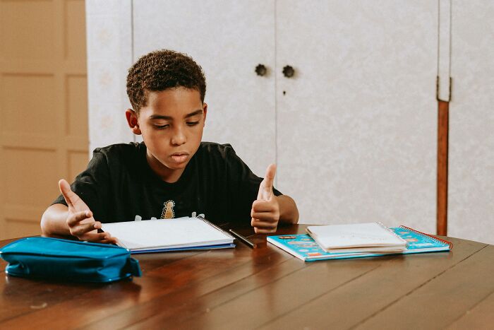 Boy studying math and science questions at a table, focused on beating the average 8th-grade student's level.