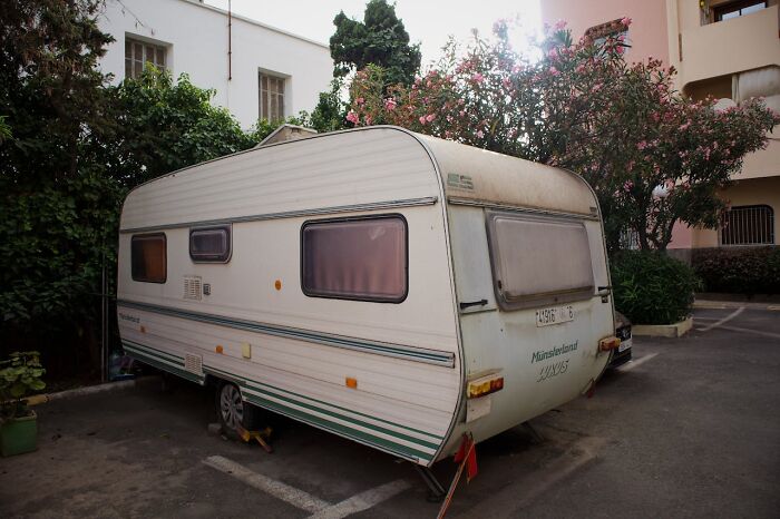 Old caravan blocked in a parking space, demonstrating a brilliantly sneaky act of revenge in an urban setting.