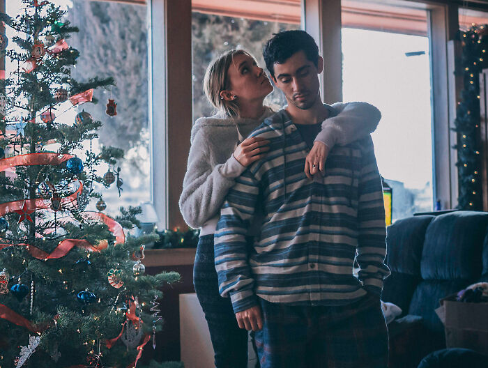 Couple during holidays near Christmas tree, highlighting how partner's holiday gift reveals painful relationship truth.