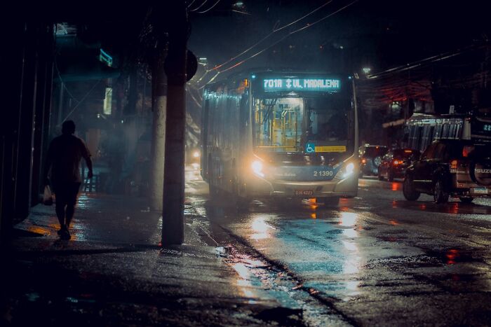 A person walking alone on a wet, dimly lit street at night, evoking instinctively feeling something was wrong.