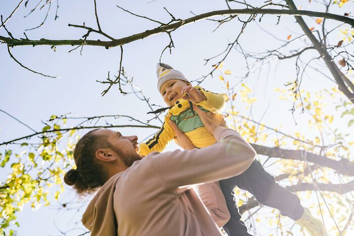 Man lifting baby in the air outdoors, capturing people online sharing stories of small decisions changing their lives.