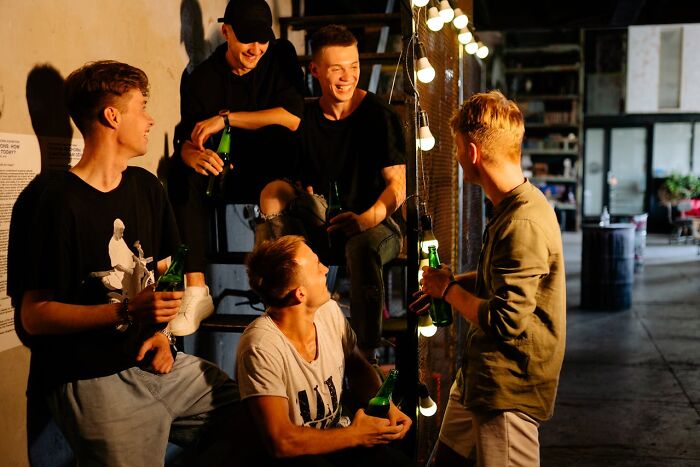 Group of young people drinking beer and socializing indoors with string lights, capturing moments of instinctive feelings something was wrong.