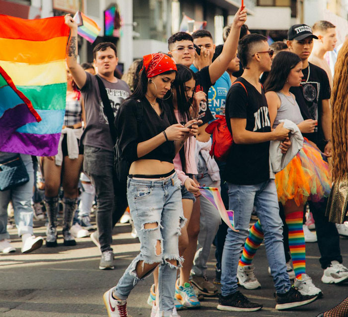Teen at a pride march holding a rainbow flag, showcasing courage and respect in a gay teen's powerful message.