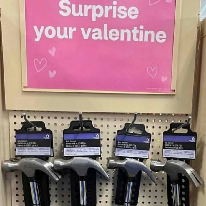 Display of hammers hanging below a pink sign encouraging to surprise your valentine, a random pic that makes you laugh