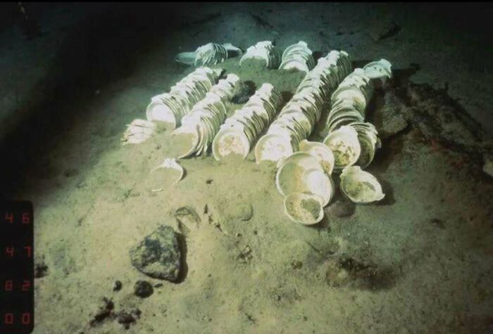 Underwater scene showing classic historical porcelain plates scattered on the ocean floor in an iconic historical picture.