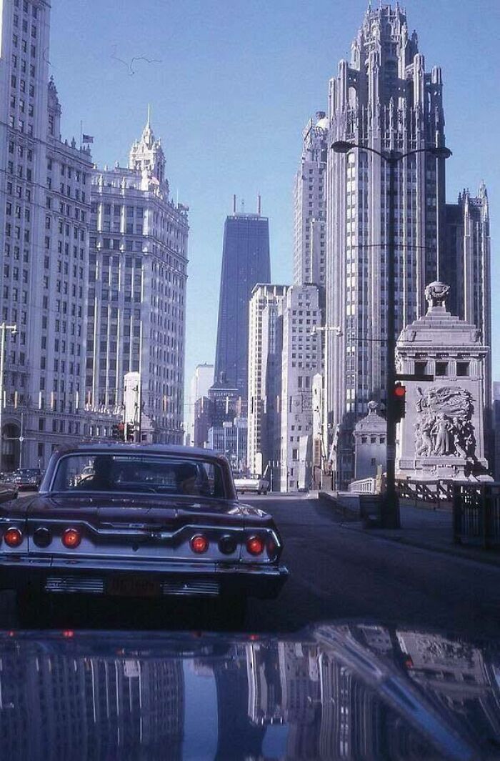 Classic and iconic historical picture of vintage cars and towering skyscrapers in a cityscape on a clear day.