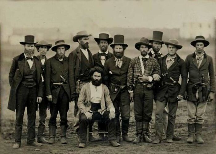 Group of men in classic 19th century western attire posing for a historical picture outdoors, showcasing iconic vintage style.