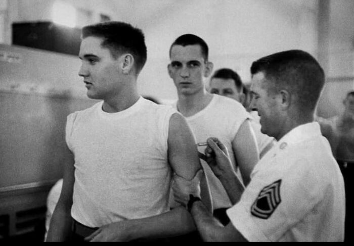 Black and white historical picture of young men in a military clinic receiving vaccinations, iconic classic moment captured.
