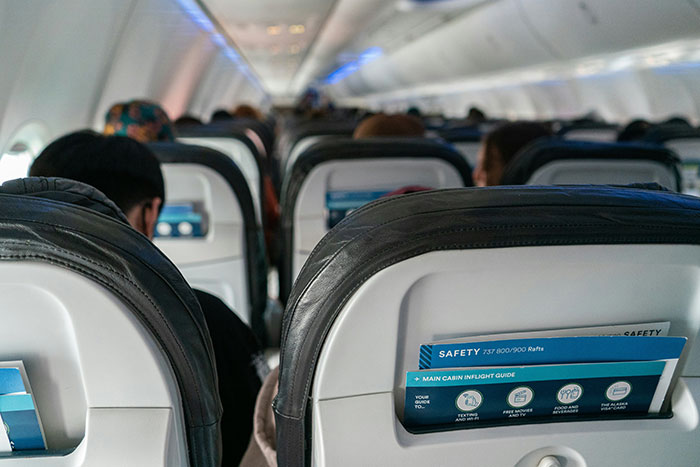 Passengers seated on a flight with focus on airplane seats and safety cards during in-flight moments.