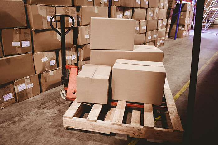 Stacked cardboard boxes on a pallet in a warehouse, illustrating practical poor person hacks to easily save thousands.