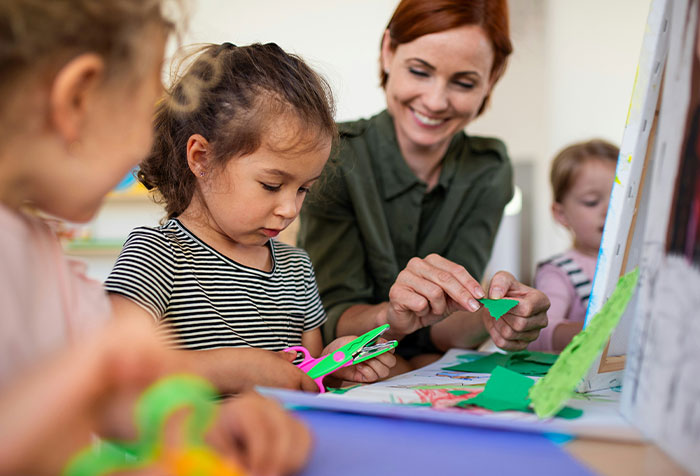 Woman guiding children in an arts and crafts activity, demonstrating acts of microfeminism and empowerment.