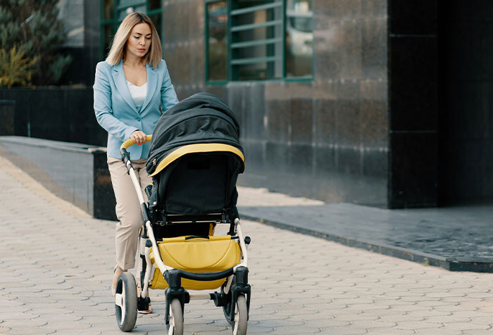 Woman pushing a stroller on a city sidewalk, symbolizing women clapping back at toxic masculinity with microfeminism acts.