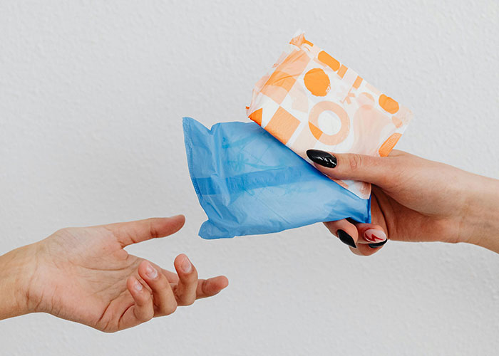 Two hands exchanging a blue plastic bag and a small orange and white package, highlighting prison life misconceptions.