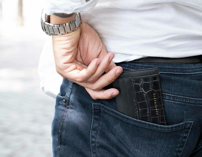 Person in white shirt placing black wallet in back pocket, illustrating habits affecting mental and physical health long-term.