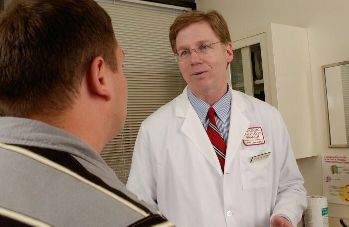 Doctor in white coat consulting patient about habits affecting mental and physical health during medical appointment