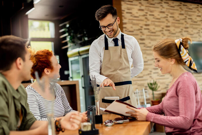 Young waiter serving customers at a restaurant, illustrating wild stories from folks who quit their jobs in record time.