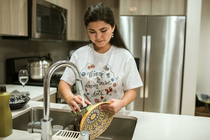 Young woman washing dishes in a modern kitchen reflecting stories from folks who quit their jobs in record time