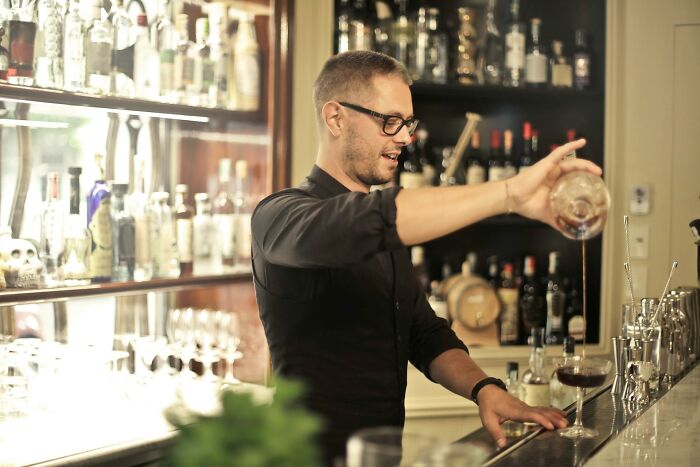 Man pouring a drink behind a bar, illustrating wild stories from folks who quit their jobs in record time.
