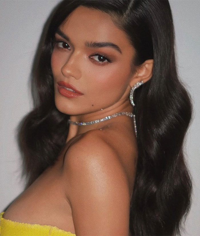 Rachel Zegler posing with wavy hair, wearing sparkly earrings and necklace, showcasing see-through dress trend style. Rachel Zegler posing with wavy hair, wearing sparkly earrings and necklace, showcasing see-through dress trend style.