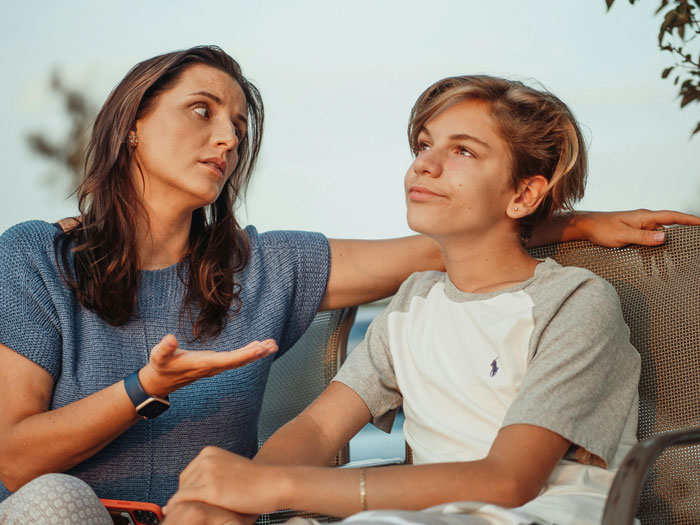 A woman having a serious talk with a teenage boy, illustrating refusing to establish relationship with fathers and kids.