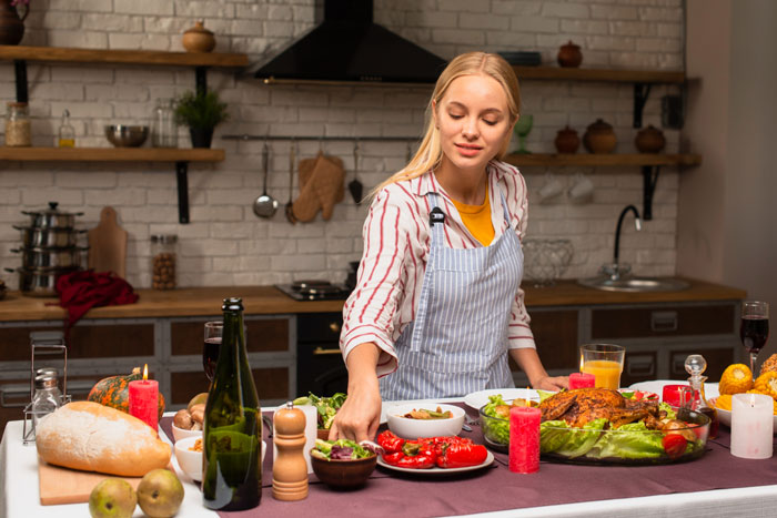 Young woman arranging Christmas menu dishes at table, illustrating picky eater demands and family meal adjustments.